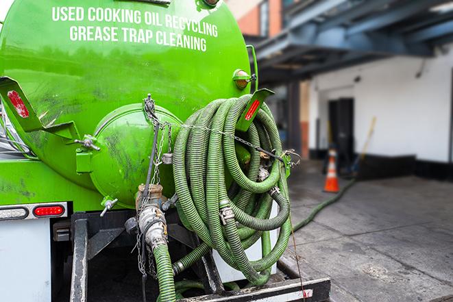 a technician pumping a grease trap in a commercial building in Lauderhill